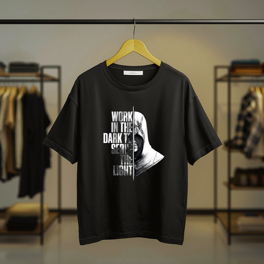 Black T-shirt featuring a hooded Assassin with the "Work in the Dark to Serve the Light" quote as a centered front print.